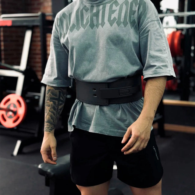 Atleta con remera gris oversize usando el Cinturón Forge ajustado en el gimnasio
